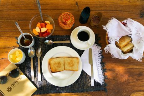 A beautifully set table with organic food, freshly prepared by the chef at Nimmu House, accompanied by a booklet featuring Nimmu House