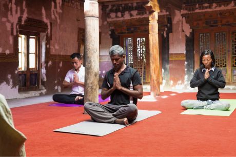A group performing morning yoga as part of the Charms Tour by Nimmu House, set in the serene courtyard of Nimmu House