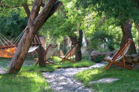 A tranquil seating area with laid-back chairs and hammocks nestled in the lush orchards of Nimmu House