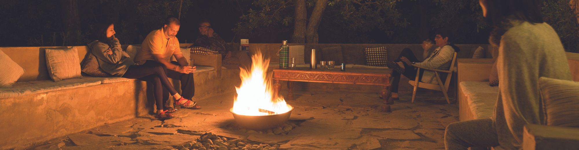 Guests relaxing around a bonfire area at Nimmu House, surrounded by nature under the night sky